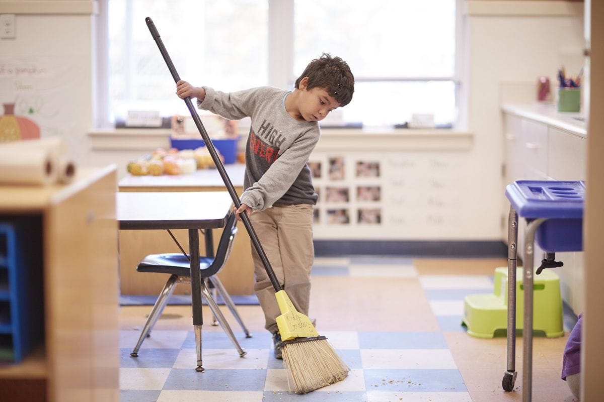 boy sweeping living room